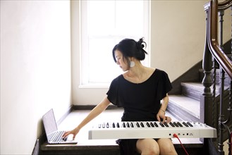 Taiwanese woman playing keyboard on staircase