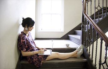 Taiwanese woman using laptop on staircase