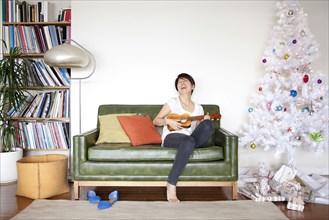 Japanese woman playing ukulele near Christmas tree