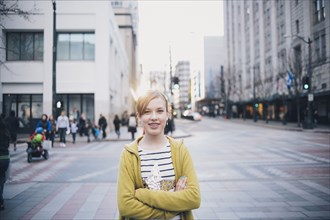 Teenage girl standing with arms crossed in city intersection