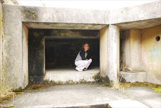 Girl crouching in concrete cubby