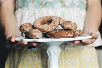 Woman holding plate of homemade donuts
