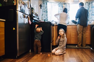 Children playing as parents cook in kitchen