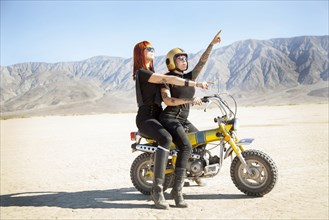 Women sitting on motorcycle in desert