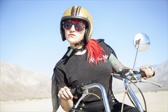 Woman sitting on motorcycle in desert