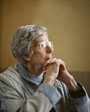 Caucasian woman resting chin on clasped hands