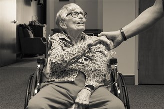 Senior woman in wheelchair shaking hand of man