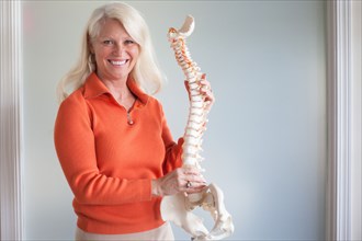 Caucasian chiropractor holding model spine