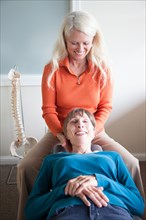 Caucasian chiropractor massaging neck of client