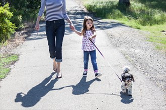 Mother and daughter walking puppy on path
