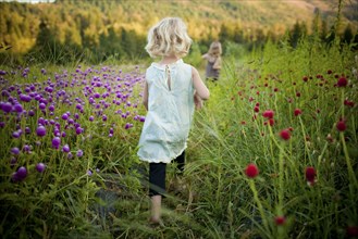 Girl walking in rural field of flowers