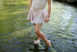 Girl standing barefoot in pond
