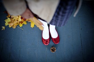 Girl wearing red slippers near pinecone