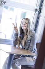 Girl giving peace sign at table
