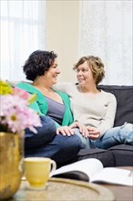 Lesbian couple relaxing on sofa in living room