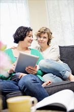 Lesbian couple using digital tablet on sofa in living room