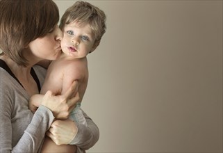 Close up of woman kissing son on cheek