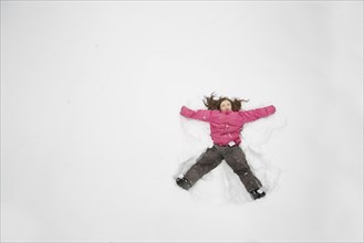 Caucasian girl making snow angel