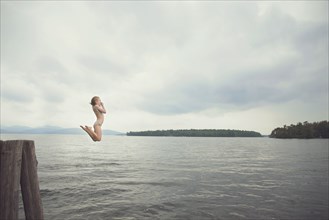 Caucasian girl jumping in remote lake