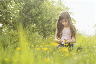 Caucasian girl picking flowers in rural field