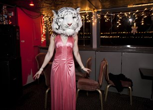 Woman wearing evening gown and tiger mask in bar