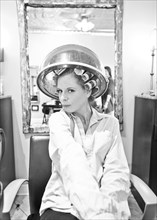 Woman sitting under hair dryer in salon