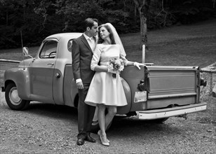 Bride and groom smiling near vintage truck