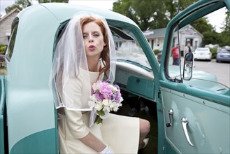 Bride blowing a kiss from vintage truck