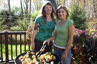 Women grilling kebabs in backyard