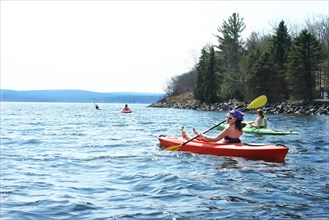 Friends rowing kayaks in lake