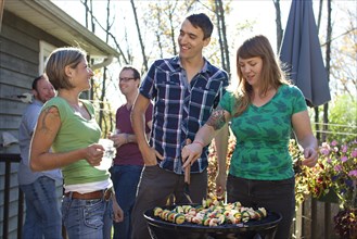 Friends grilling vegetables in backyard