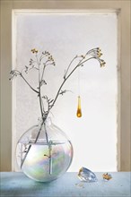 Glass ornament hanging from plants in glass vase