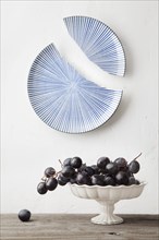 Grapes on platter under broken ceramic plate