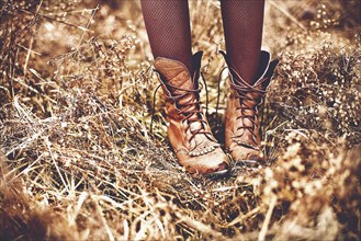 Boots of Caucasian teenage girl standing in tall grass