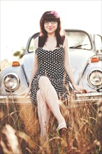 Caucasian teenage girl sitting on  vintage car