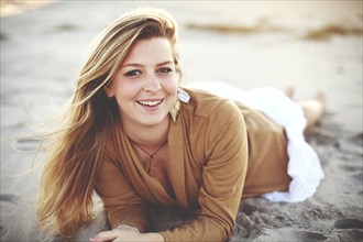 Close up of smiling woman laying on beach
