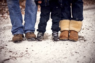 Close up of boots of family standing in snow