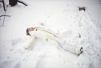 Caucasian girl making snow angel in field