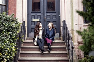 Caucasian teenage girls laughing on front stoop