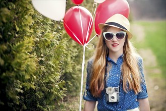 Caucasian woman carrying balloons and instant camera