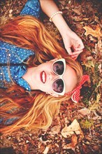 Caucasian woman laying in autumn leaves