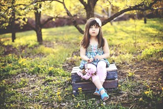 Girl sitting on crate in orchard
