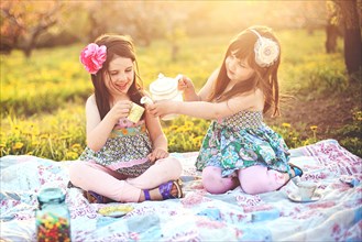 Girls having tea party picnic in rural field