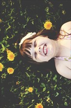 Smiling girl laying in grass with flowers