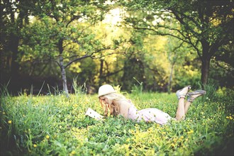 Woman reading book and laying in rural field
