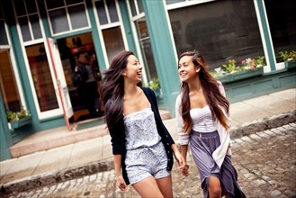 Laughing women crossing cobblestone street