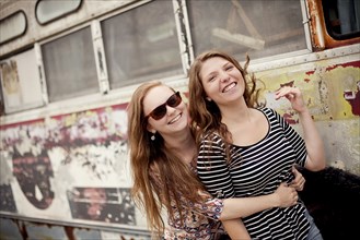 Smiling girls hugging near dilapidated bus