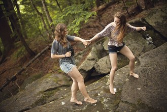Girls walking barefoot on boulder in forest