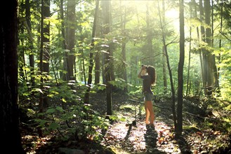 Girl looking through binoculars in forest