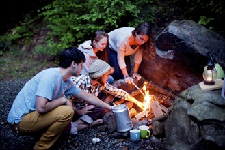 Friends roasting marshmallows over forest campfire